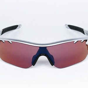 May include: Silver framed sunglasses with red tinted lenses. The sunglasses have a sporty design with a curved frame.