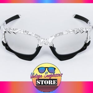May include: White and black patterned sunglasses with a black frame and arms. The lenses are clear. The image includes a logo for Vintage Sunglasses Store.