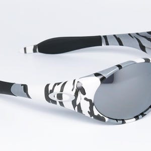 May include: Gray and white patterned sunglasses with gray lenses. The frames have a zebra-like pattern in black, gray, and white. The arms have black rubber grips for comfort. A stylish accessory for eye protection.