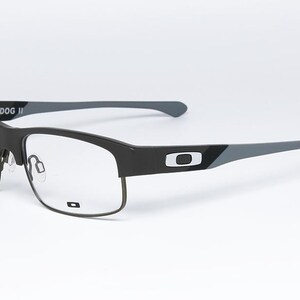 May include: Black and gray rectangular eyeglasses with clear lenses. The frames have a matte finish with the brand name "YARDDOG II" on the temple. The temples are gray with a black accent and the brand logo.