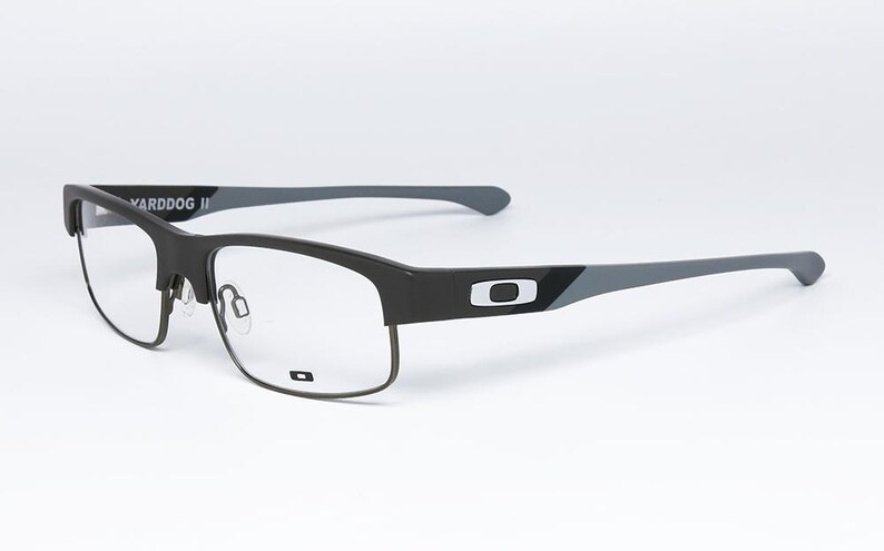 May include: Black and gray rectangular eyeglasses with clear lenses. The frames have a matte finish with the brand name "YARDDOG II" on the temple. The temples are gray with a black accent and the brand logo.