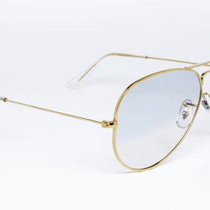 Op de afbeelding: Gouden aviator zonnebril met lichtblauwe gradient glazen.