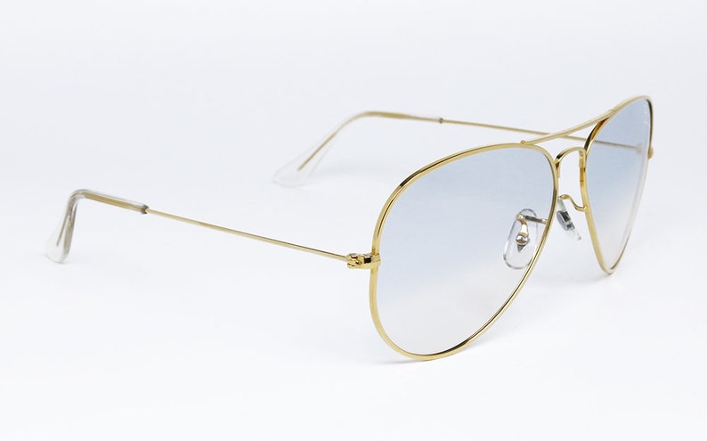 Op de afbeelding: Gouden aviator zonnebril met lichtblauwe gradient glazen.