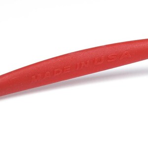 May include: A red tool with the text "MADE IN USA" printed on the handle. The tool has a gray tip on each end. The handle is a bright red color.