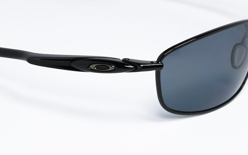 Puede incluir: Gafas de sol negras con un dise&ntilde;o elegante y moderno. Las monturas son negras con un logotipo sutil en la patilla. Las lentes son de color gris oscuro, proporcionando sombra y protecci&oacute;n solar. Un accesorio elegante para actividades al aire libre.