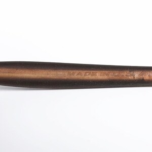 May include: A pen with a silver tip and a brown handle. The handle has the text "MADE IN U.S.A." engraved on it. The pen is set against a white background.