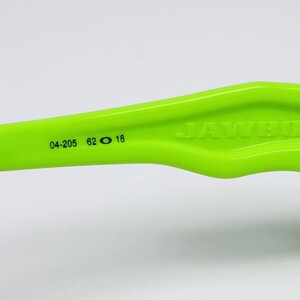 May include: Close-up of a neon green bicycle component with the word "JAWBONE" embossed on the side. The component has black accents and the numbers "04-205 62 18" printed on it. The background is white.