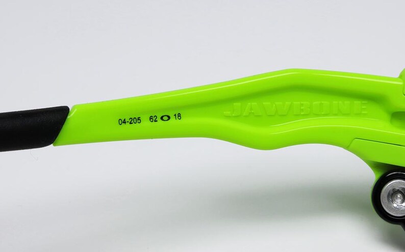 May include: Close-up of a neon green bicycle component with the word "JAWBONE" embossed on the side. The component has black accents and the numbers "04-205 62 18" printed on it. The background is white.