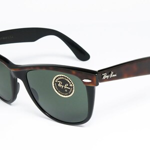 K&ouml;nnte beinhalten: Braune Schildpatt-Ray-Ban-Sonnenbrille mit gr&uuml;nen Gl&auml;sern. Die Sonnenbrille hat einen schwarzen Rahmen und ein silbernes Ray-Ban-Logo am rechten B&uuml;gel.