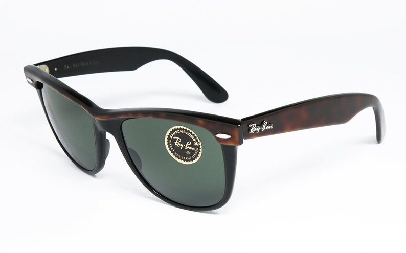 K&ouml;nnte beinhalten: Braune Schildpatt-Ray-Ban-Sonnenbrille mit gr&uuml;nen Gl&auml;sern. Die Sonnenbrille hat einen schwarzen Rahmen und ein silbernes Ray-Ban-Logo am rechten B&uuml;gel.