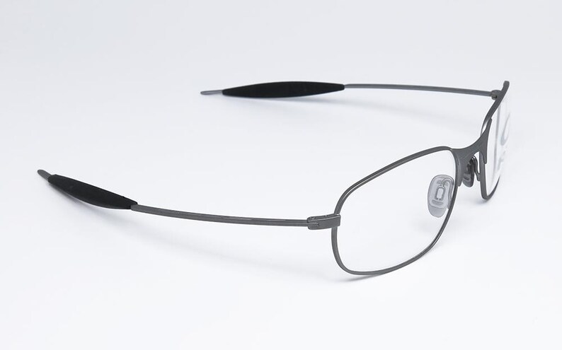 May include: A pair of silver-toned metal eyeglasses with clear lenses. The glasses have a thin, wire frame and black rubber earpieces.