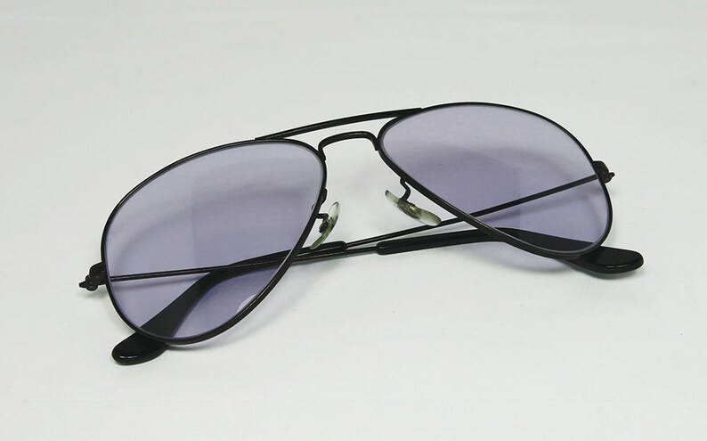 May include: Black aviator sunglasses with a dark purple lens.