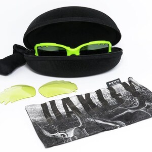 May include: A set of neon green sports sunglasses with a black case, two extra yellow lenses, and a black and white patterned carrying pouch. The sunglasses are in an open black case.