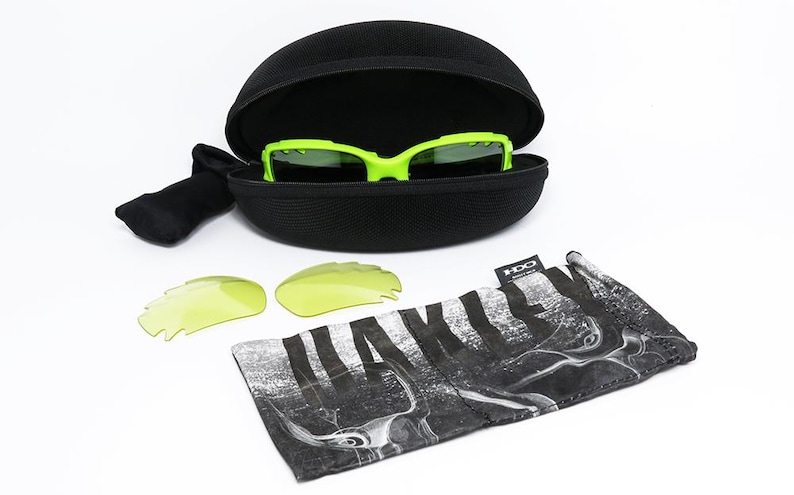 May include: A set of neon green sports sunglasses with a black case, two extra yellow lenses, and a black and white patterned carrying pouch. The sunglasses are in an open black case.