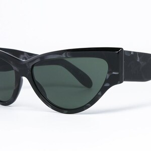 May include: Black cat-eye sunglasses with a marbled frame and dark lenses.