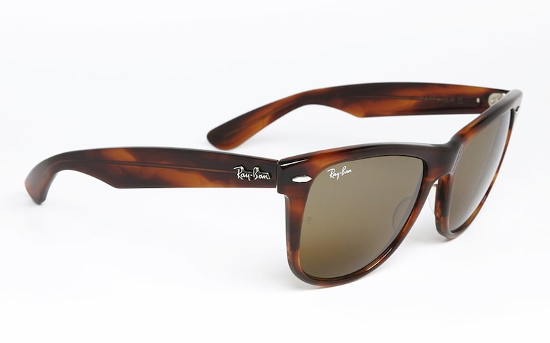 Peut inclure: Lunettes de soleil Ray-Ban en &eacute;caille de tortue brune avec des verres bruns. Les lunettes ont une monture de style Wayfarer classique.