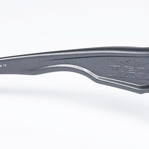 May include: Close-up of a gray sunglass arm with the word "TEN" embossed on the side. The arm also has the numbers "009128-08 61 16" printed on it. The sunglasses are likely for outdoor activities.