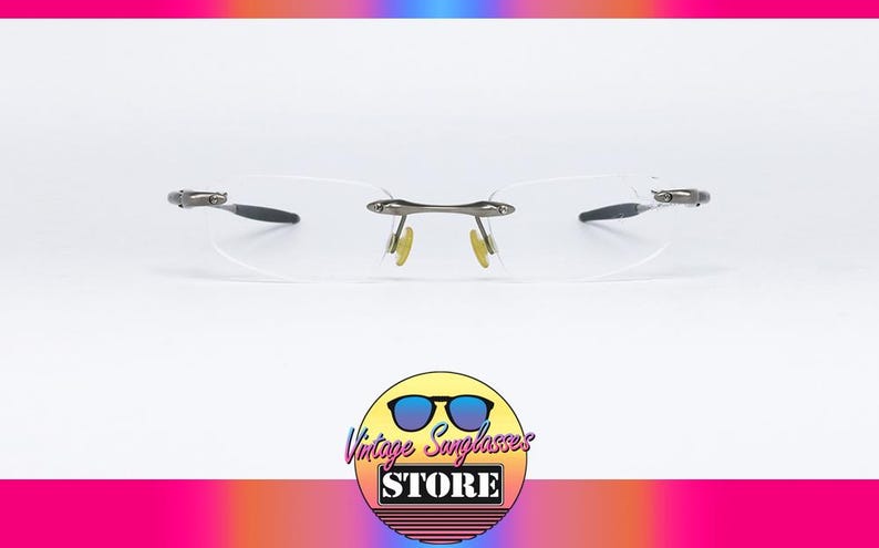 May include: A pair of rimless, silver-toned eyeglasses with clear lenses. The glasses have a simple, modern design.