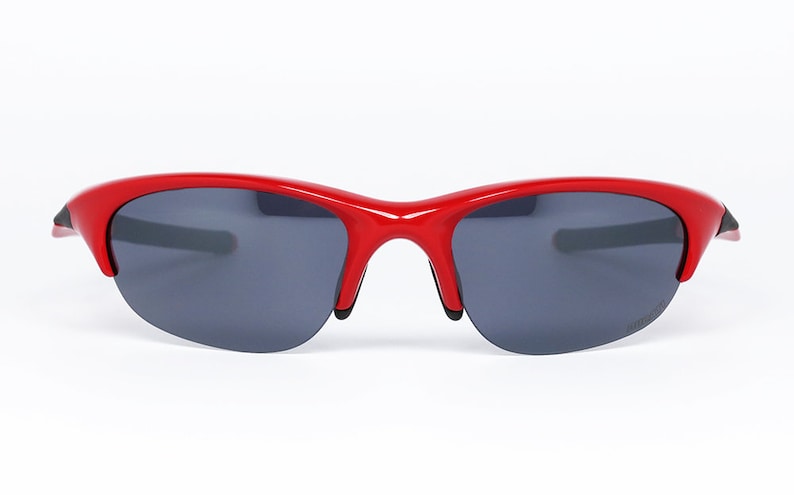 Puede incluir: Gafas de sol rojas con lentes gris oscuro. Las gafas tienen un dise&ntilde;o curvo y deportivo con un acabado brillante. La montura es de color rojo vibrante y las lentes son de color gris oscuro. Las gafas est&aacute;n dise&ntilde;adas para actividades al aire libre.