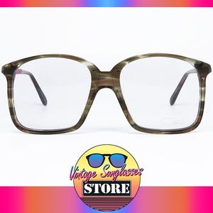 Könnte beinhalten: Vintage Brille mit quadratischem Rahmen in einem marmorierten Grün- und Braunmuster. Die Brille hat klare Gläser und dunkle Bügel. Das Logo von Vintage Sunglasses Store befindet sich unten.