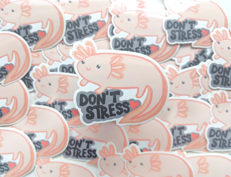 May include: A collection of stickers featuring a cartoon axolotl in shades of peach and pink. Each sticker has the text "DON'T STRESS" in a gray bubble with a red heart. The axolotl has a smiling face and detailed gills.