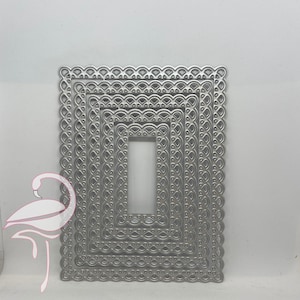 May include: Set of five silver metal rectangle-shaped die-cut frames with intricate scalloped edges. The frames are nested inside each other, creating a layered effect.