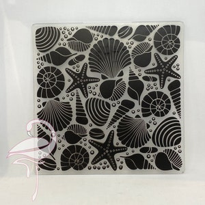 Puede incluir: Una lámina de acrílico transparente con un diseño en blanco y negro de conchas y estrellas de mar. El diseño se repite en toda la lámina.