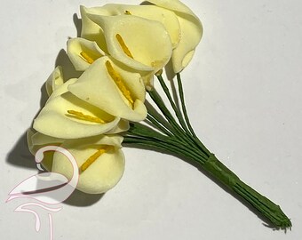 Op de afbeelding: Een bos van 10 crèmekleurige kunstmatige calla lelies met gele centra en groene stelen.