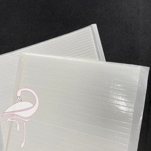 May include: Two white sheets of double-sided adhesive tape with a grid pattern. The tape is designed for crafts and other projects.