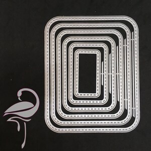 May include: A set of nine silver metal rectangle-shaped die-cut frames with a stitched edge design. The frames are nested inside each other, with the smallest frame in the center.