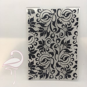 Może przedstawiać: Przezroczysty szablon z tworzywa sztucznego z czarnym wzorem kwiatowym. Wzór zawiera skomplikowane wiry i liście.