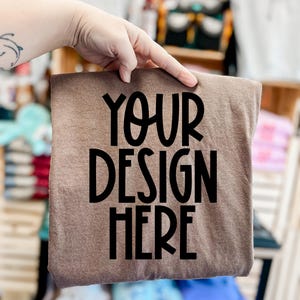May include: A brown t-shirt with the text "YOUR DESIGN HERE" printed in black.