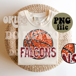 Puede incluir: Camiseta color crema con un diseño de baloncesto con purpurina naranja y la palabra "FALCONS" en purpurina roja. La camiseta también tiene el texto "PNG file" en un círculo negro.