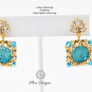Può includere: Un paio di orecchini di loto color acquamarina e oro con un design a fiore di cristallo. Gli orecchini sono realizzati con perline e presentano un cristallo acquamarina di forma quadrata al centro.