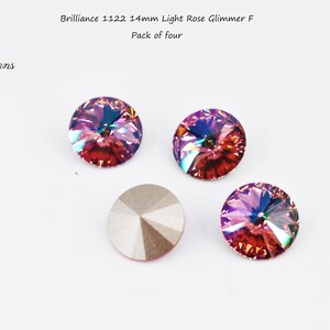 May include: Four 14mm light rose glimmer F brilliance crystals in a pack of four. The crystals are iridescent and have a pink and purple hue.