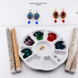 May include: Two pairs of beaded earrings with crystal accents. The earrings are displayed on a white palette with various colors of beads in small containers. The text "Regalia Earrings Colorways (c)2023" and "Shri Designs" are visible in the image.