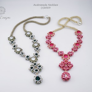 Könnte beinhalten: Zwei Perlenketten mit einer goldenen Kette und einem Anhänger. Eine Kette hat weiße und grüne Perlen, die andere rosa Perlen. Die Ketten liegen auf einem weißen Hintergrund. Andromeda Halskette (c)2023 Shrii Designs.