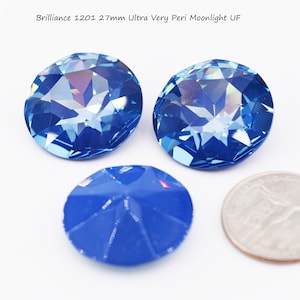 May include: Two 27mm blue crystal rhinestones with a single blue rhinestone in the background. Brilliance 1201 Ultra Very Peri Moonlight UF.