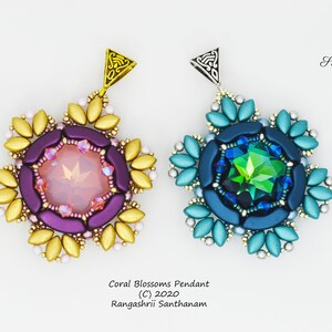May include: Two beaded pendants with a snowflake design. The pendant on the left has a pink and purple center with a gold outer ring. The pendant on the right has a blue and green center with a silver outer ring. Both pendants have a crystal in the center.
