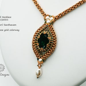 Könnte beinhalten: Eine Valli-Halskette in Smaragd- und Roségold, mit einem großen grünen Edelstein, umgeben von goldenen Perlen und einem Perlenanhänger. Die Halskette wurde von Rangashrii Santhanam hergestellt und ist urheberrechtlich geschützt 2021.