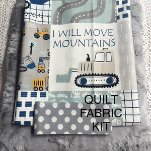 May include: A quilt fabric kit with a gray, white, and blue color scheme. The kit includes a variety of fabrics with different patterns, including polka dots, stripes, and a design featuring construction vehicles. The fabric with the construction vehicles has the text "I Will Move Mountains" and a picture of a bulldozer. The kit also includes a gray faux fur fabric.
