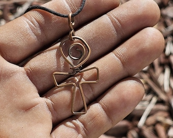May include: A copper-colored Ankh pendant necklace with a black cord. The Ankh is a symbol of eternal life in ancient Egyptian mythology.