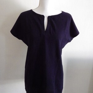 May include: A dark purple, short-sleeved, v-neck tunic top on a white mannequin.