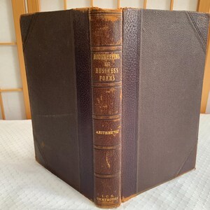 May include: An antique book titled "Bookkeeping and Business Forms" with "Arithmetic" on the spine. The book has a brown leather spine and dark brown covers. The book is a textbook from L.C. Smith Textbooks.
