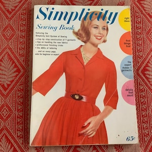 May include: A vintage Simplicity Sewing Book cover featuring a woman wearing a red dress with a white collar and a black belt. The cover has the title "Simplicity Sewing Book" and features several colorful circles with text such as "right ideas", "first things first", "the expert makes 7 garments", and "details that count". The price is listed as "65c".