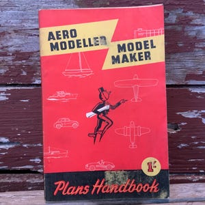 May include: Vintage "Aero Modeller Model Maker" Plans Handbook. The red cover features illustrations of various vehicles and aircraft, with the text "Plans Handbook" at the bottom. A cartoon figure points to a blueprint.