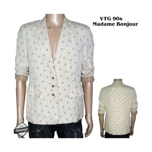 May include: A vintage 90s cream-colored blazer with a brown floral pattern. The blazer has a notched collar, long sleeves, and a button closure. The text "VTG 90s Madame Bonjour" is visible in the image.