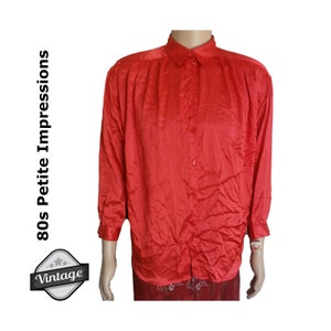 May include: A red satin long-sleeve button-up shirt with a collar. The shirt is labeled "80s Petite Impressions Vintage".