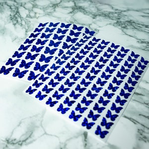 May include: Sheets of white paper with blue glitter butterfly stickers.