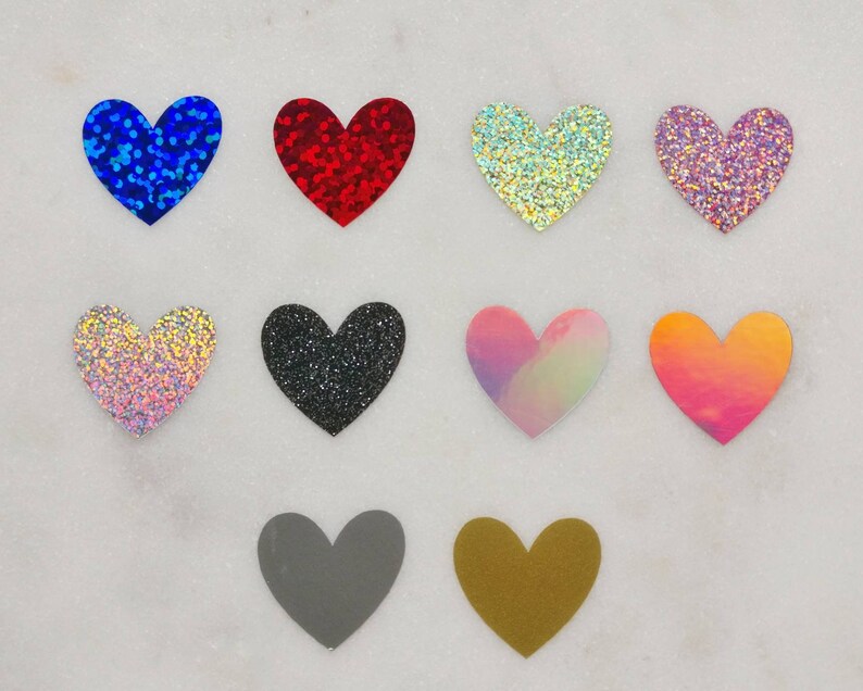 May include: Ten heart-shaped craft supplies in various colors and finishes, including glitter, iridescent, and solid colors. The hearts are arranged in two rows of five.